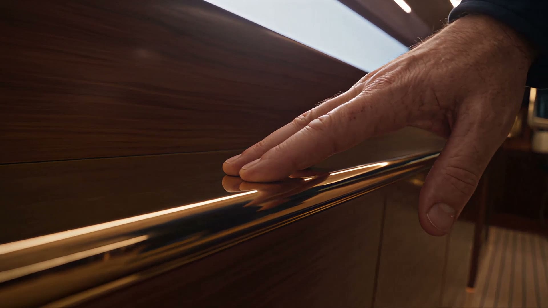 A hand running along the polished mahogany handrail.