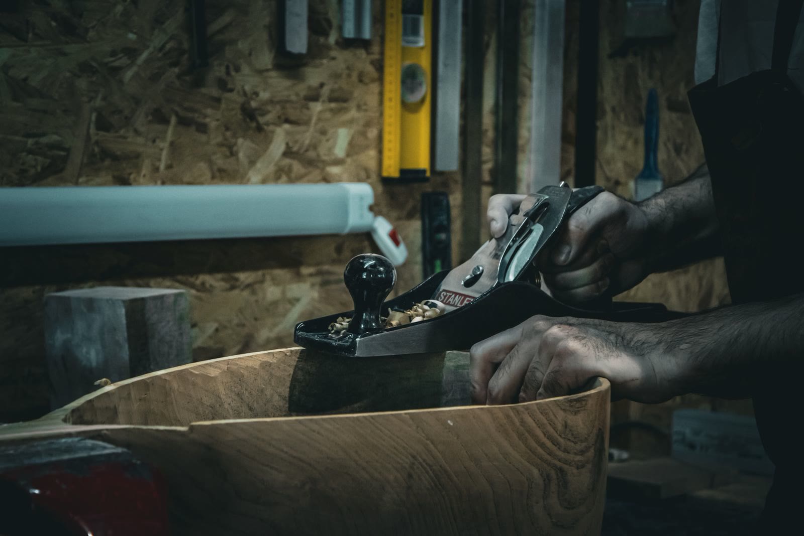 A hand plane working a curved piece of timber in the workshop.