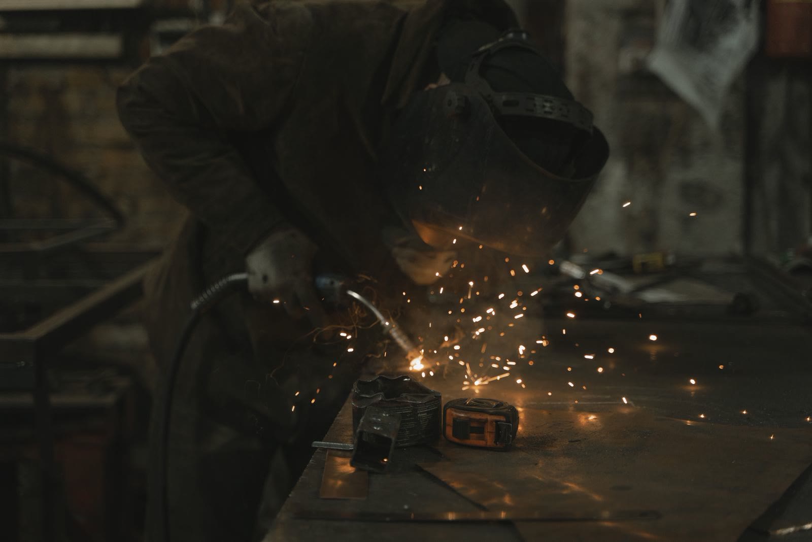 A welder at work, sparks in the half-light of the workshop.
